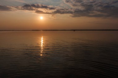 Gölde gün batımı. Güzel bulutlarla dolu akşam gökyüzü gölün suyuna yansıyor.