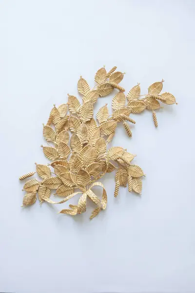 The branch with leaves is made of straw. Straw wall decoration. The products are made of straw. Decoration of straw on an white background