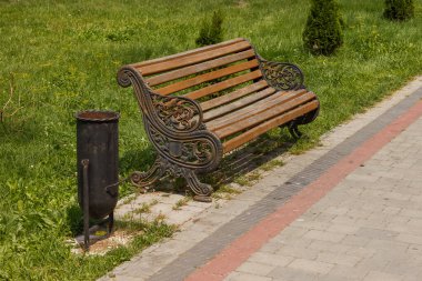 Parkta bir bank ve çöp tenekesi. Güneşli bir gün