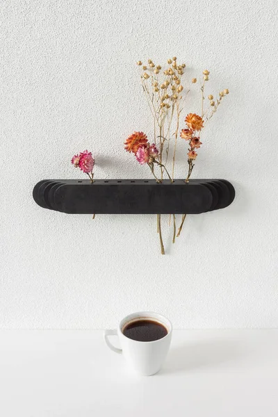 Wall vase for dried flowers and a cup of coffee.