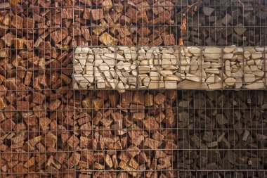 Gabion çitinin dokusu doğal taş ve metal ağdan yapılmıştır.