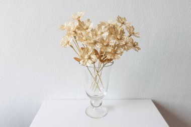 Beyaz arka planda samandan yapılmış bir buket çiçekli cam bir vazo.