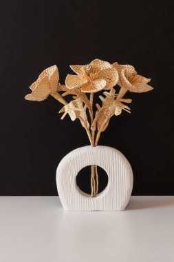 Siyah arka planda samandan yapılmış bir buket çiçekli ahşap bir vazo. Samandan örgü