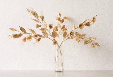 Beyaz arka planda samandan yapılmış bir buket çiçekli cam bir vazo. Samandan örgü