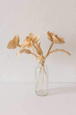 Beyaz arka planda samandan yapılmış bir buket çiçekli cam bir vazo. Samandan örgü