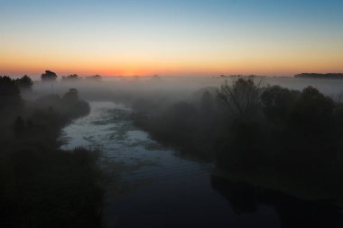 Güneşin doğuşu sisli nehirde