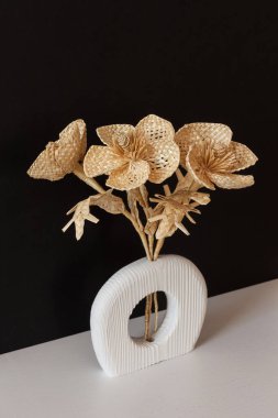 Siyah arka planda samandan yapılmış bir buket çiçekli ahşap bir vazo. Samandan örgü