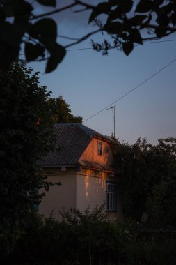 Akşam güneşiyle aydınlatılmış eski ahşap bir ev. Kırsal alan.