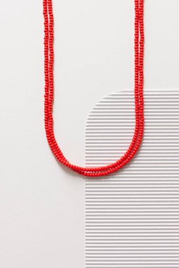 Beyaz arka planda kırmızı boncuklu bir kolye.