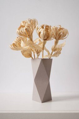 Çiçekler arka plandaki samandan yapılmıştır. Çiçekler mukavva bir vazodaki samandan yapılmıştır. Samandan örgü