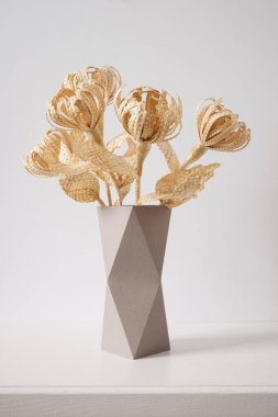 Çiçekler arka plandaki samandan yapılmıştır. Çiçekler mukavva bir vazodaki samandan yapılmıştır. Samandan örgü