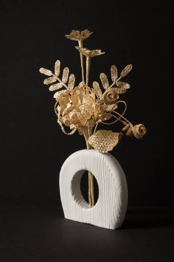 Siyah arka planda samandan yapılmış bir buket çiçekli ahşap bir vazo. Samandan örgü