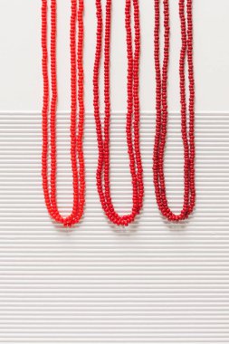 Beyaz arka planda kırmızı boncuklu bir kolye. Üst görünüm.