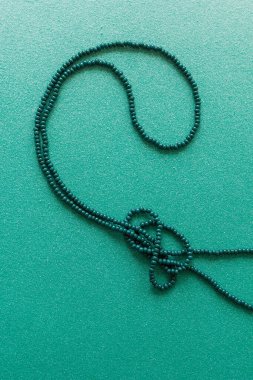 Yeşil arka planda yeşil boncuklu bir kolye. Üst görünüm.