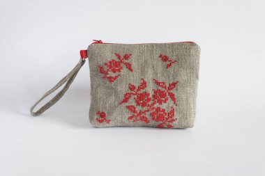 Keten kumaştan yapılmış ve kırmızı ipliklerle işlenmiş makyaj çantası. Hafif arkaplan.