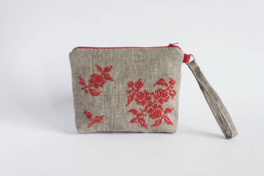 Keten kumaştan yapılmış ve kırmızı ipliklerle işlenmiş makyaj çantası. Hafif arkaplan.