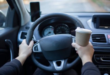 Arabada kahve bardağı tutan adam.