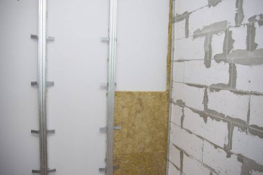 İşçi duvarları mineral yünüyle yalıtıyor ki daha fazla alçıyla kaplansın. Sıcaklık yalıtımı ve konutların ses yalıtımı.