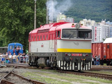 An old diesel locomotive stands on the tracks at the train station.