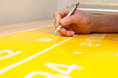 Close-up of a man's hand making a car sticker from yellow foil