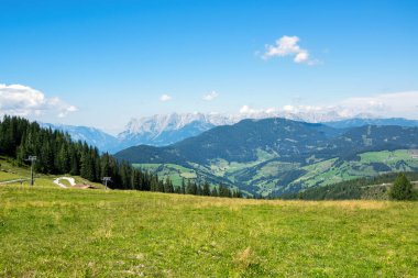 Panorama of Austrian Alps with forest and green meadow. Grafenberg Hill, Wagrain.