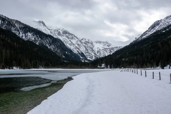 Snowy Jagersee lake with ice under mountains in winter in Austrian Alps.