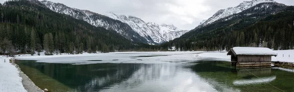 Snowy Jagersee lake with ice under mountains in winter in Austrian Alps.
