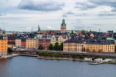 Stockholm, İsveç - 20 Temmuz 2015: Kuleli şehir silueti, liman ve ana yoldaki eski evler. Deniz kanalında rıhtım ve liman.
