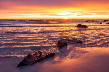 Aydınlatılmış su ve kumlu plajlı gün batımı - Skagen, Lofoten, Norveç.