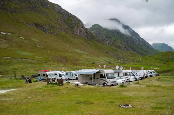 stock image Lofoten, Norway - July 15, 2015: A group of camper vans stand under the mountains on the green grass by the beach.