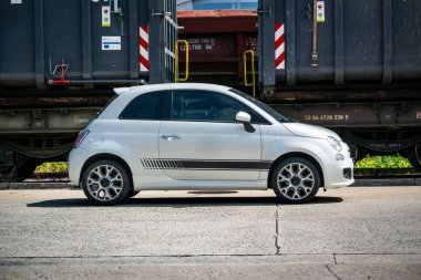 Brno, Çek Cumhuriyeti - 20 Mayıs 2023: Küçük beyaz bir İtalyan arabası eski ütülenmiş vagonların önüne park edilmiştir.. 