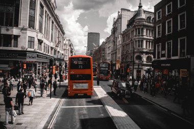 Londra, İngiltere - 18 Temmuz 2012: Kırmızı çift katlı otobüsler ve şehir merkezindeki caddede siyah bir taksi. İnsanlar eski binalar boyunca kaldırımlarda.