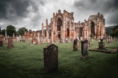 Karanlık ve ürkütücü Melrose Abbey Katedrali İskoçya 'da mezarlık ve taş mezarlarla.