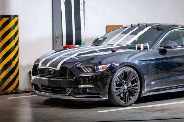 Brno, Çek Cumhuriyeti - 12 Eylül 2023: Siyah bir Ford Mustang 'in garajına folyo şeritlerinin yapıştırılması ve yapıştırılması. Vinil çıkartmalardan çıkartmalar.