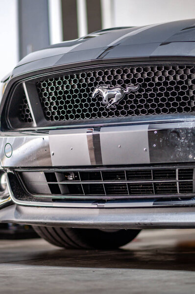 Brno, Czech Republic - September 12, 2023: Detail of the front bumper and radiator of a Ford Mustang car with a logo and stripes made of matte black foil.