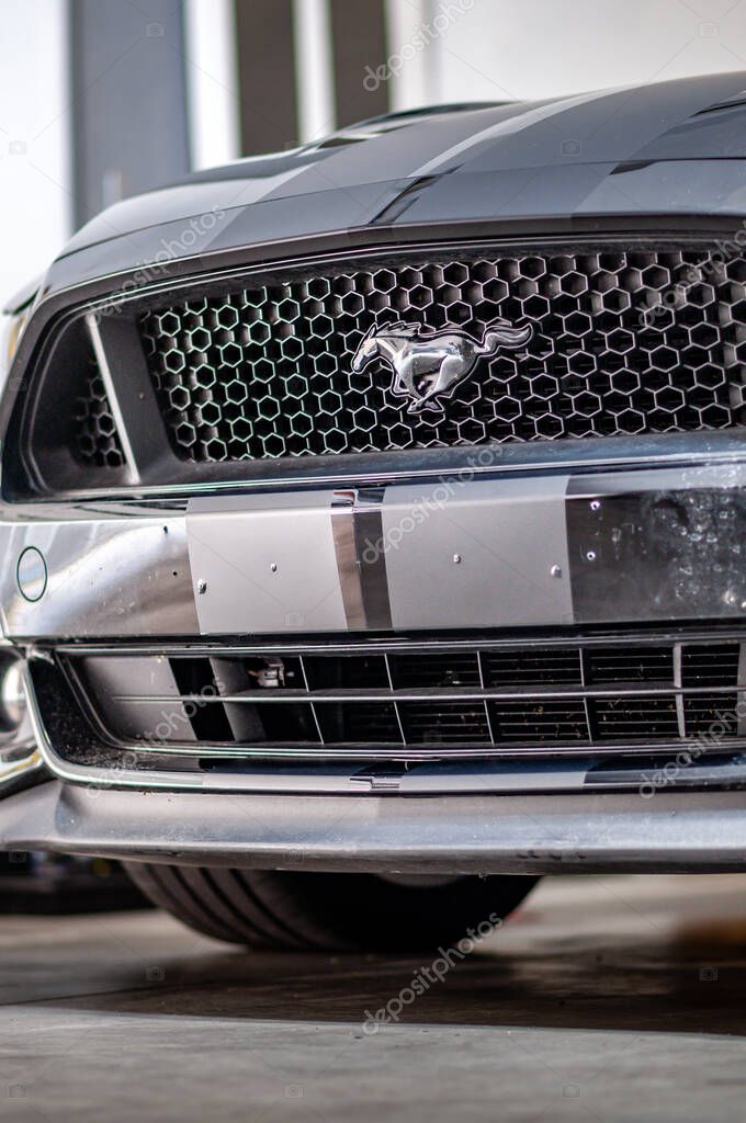 Brno, Czech Republic - September 12, 2023: Detail of the front bumper and radiator of a Ford Mustang car with a logo and stripes made of matte black foil.