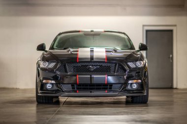 Brno, Çek Cumhuriyeti - 12 Eylül 2023: Gri ve kırmızı folyo şeritli siyah renkli Ford Mustang spor kaslı araba. Hızlı bir araba garajda park halinde..