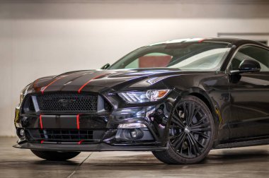 Brno, Çek Cumhuriyeti - 12 Eylül 2023: Gri ve kırmızı folyo şeritli siyah renkli Ford Mustang spor kaslı araba. Hızlı bir araba garajda park halinde..
