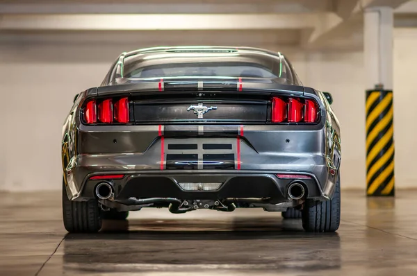 Brno, Çek Cumhuriyeti - 12 Eylül 2023: Siyah ve kırmızı folyo çizgili gri renkli Ford Mustang spor kaslı arabasının arka planı. Hızlı bir araba garajda park halinde..