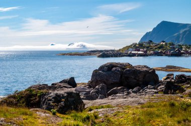 Norveç 'teki Lofoten adasında kayalar ve denizle kaplı bir körfez. Sahilde ahşap evleri olan küçük bir balıkçı köyü..