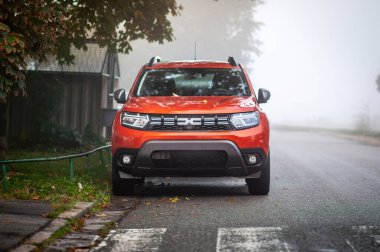 Turuncu Dacia Duster kışın siste kaldırıma park etmiş.
