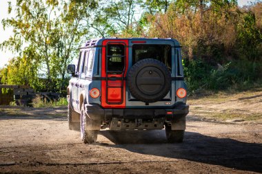 Ineos Grenadier 'in arazi aracı ormanın içinde, ağaçların arasındaki toprak yolda.