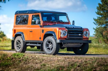 Brno, Çek Cumhuriyeti - 15 Ekim 2023: Orange Land Rover Defender 90 SUV yola park etti. Araba yan görünümü.