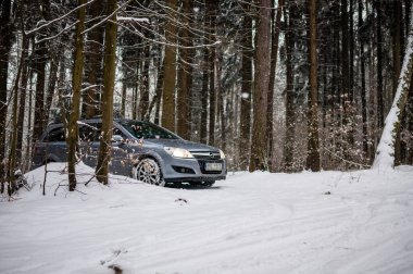 Gri Opel Astra arabası kışın ormanda ve karlı orman yollarında..
