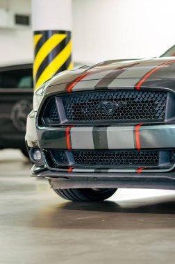 Brno, Czeh Cumhuriyeti - 1 Kasım 2023: Gri ve kırmızı hızlı şeritli koyu yeşil bir Ford Mustang garajda park halinde..