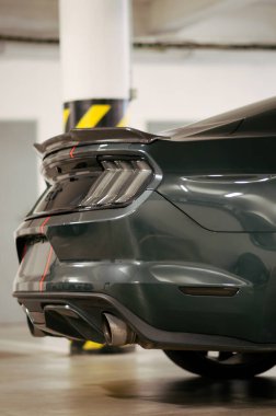 Brno, Czeh Cumhuriyeti - 1 Kasım 2023: Gri ve kırmızı hızlı şeritli koyu yeşil bir Ford Mustang garajda park halinde..
