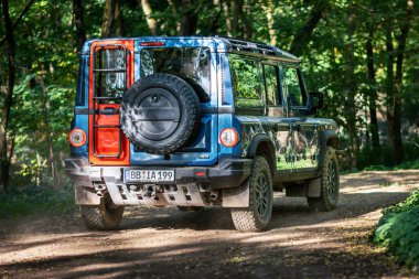 Brno, Çek Cumhuriyeti - 6 Ekim 2023: Ineos Grenadier ormandaki arazi aracı ağaçlar arasındaki toprak yolda