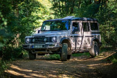 Brno, Çek Cumhuriyeti - 6 Ekim 2023: Ineos Grenadier ormandaki arazi aracı ağaçlar arasındaki toprak yolda