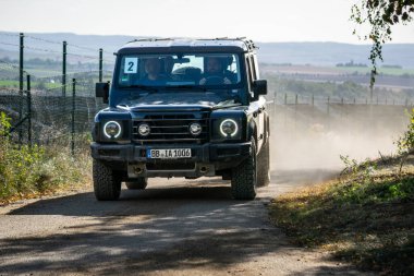 Brno, Çek Cumhuriyeti - 6 Ekim 2023: Ineos Grenadier ormandaki arazi aracı ağaçlar arasındaki toprak yolda