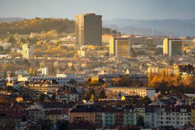 Brno, Çek Cumhuriyeti - 18 Kasım 2023: Sabah güneşiyle aydınlanan binaları ve gökdelenleri olan şehir. Sonbaharın erken saatlerinde büyük bir şehrin çatıları ve sokakları..